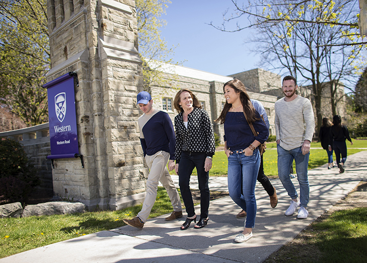 People walking by a sign that says Western