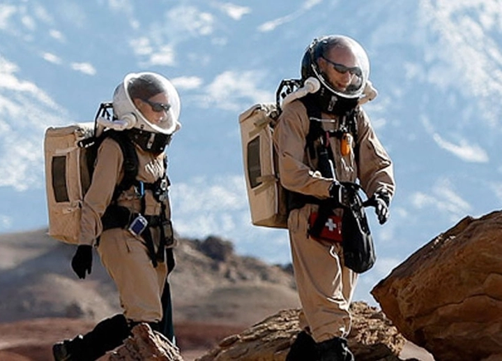 astronaut trainees walking across rocky terrain