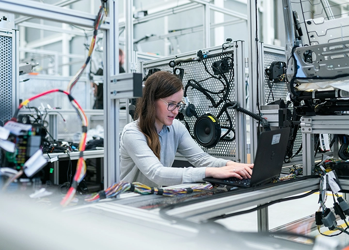 Woman working on a computer amongst large machinery